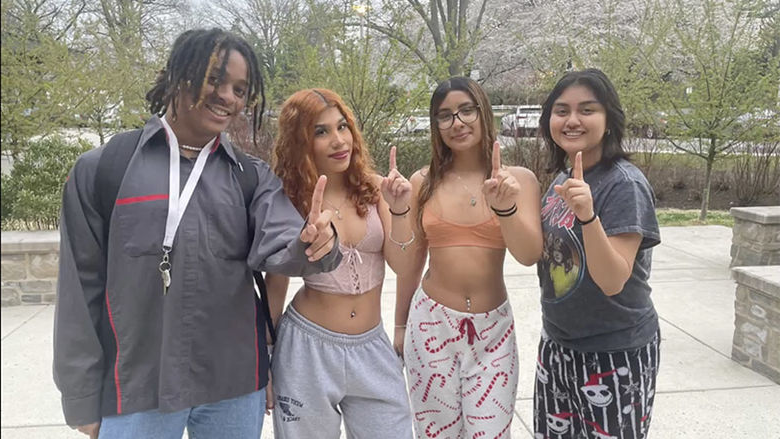 four students holding 1 finger up for "First Gen" students